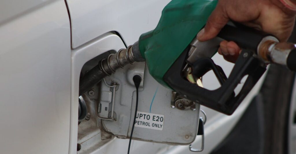 Petrol and Diesel Just Got More Expensive — And Here's Why You Should Be Worried Close-up of a hand refueling a vehicle. E20 petrol pump nozzle in use.